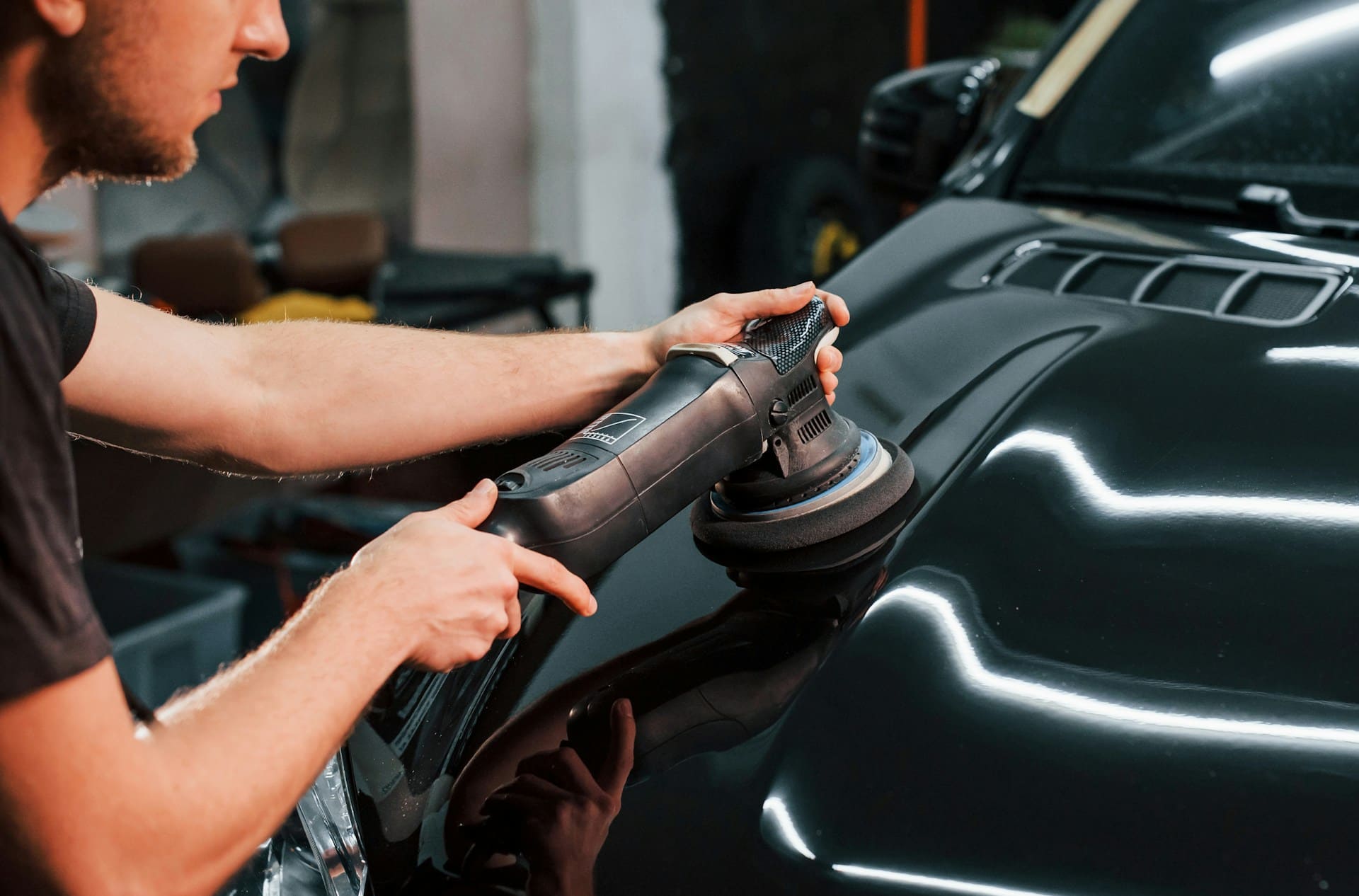 Car detailing professional polishing a vehicle with a dual-action polisher